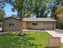 Charming home with well-manicured front yard, mature trees, and an inviting orange front door at 7092 E Mexico Ave, Denver, CO 80224