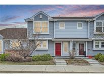 Charming townhome with a red front door, light blue siding, and manicured landscaping at 19046 E 57Th Pl # B, Denver, CO 80249