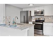 Well-lit kitchen featuring stainless steel appliances, white cabinetry and granite countertops at 3100 S Federal Blvd # 331, Denver, CO 80236