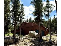 Rustic home nestled among tall trees and large boulders, featuring a two-car garage and a deck at 250 Upper Forest Rd, Idaho Springs, CO 80452