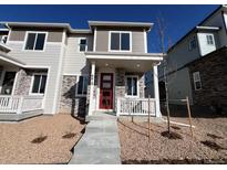 Charming townhome featuring stone accents, a red front door, and a cozy porch perfect for enjoying the neighborhood views at 6618 N Nepal Ct, Aurora, CO 80019