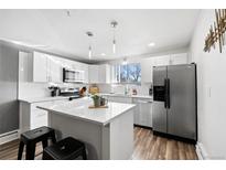 Modern kitchen with white cabinets, stainless steel appliances, and an island at 12555 W 61St Ave, Arvada, CO 80004