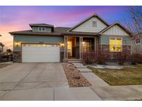 Charming home with a two-car garage, stone accents, and a manicured front yard at dusk at 23600 E Swallow Cir, Aurora, CO 80016
