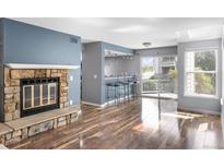 Open living room featuring hardwood floors, a stone fireplace, and access to the outdoor deck at 6861 Xavier Cir # 3, Westminster, CO 80030