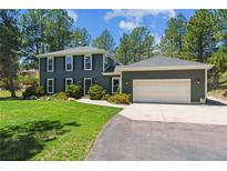 Charming two-story home with a well-manicured lawn and attached two car garage, nestled amongst mature trees at 7701 Rollins Dr, Larkspur, CO 80118