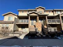 Three-story townhome featuring dual-tone siding, stone accents, elevated entrances, and well-maintained landscaping at 591 Brennan Cir, Erie, CO 80516