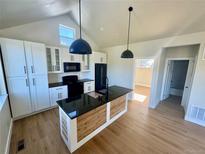 Bright kitchen features white cabinets, black appliances, granite counters and an island with wood accent at 33884 Bergen View Trl, Evergreen, CO 80439