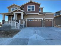 Two-story house with a brown and beige exterior, two-car garage, and a front porch at 4664 Windmill Dr, Thornton, CO 80601