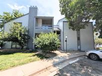 Attractive two-story condo with gray siding, chimney, manicured lawn, and lush trees at 14006 E Stanford Cir # K08, Aurora, CO 80015