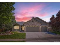 Charming home featuring a three-car garage, brick facade, front porch, and a well-maintained lawn at 10762 W 54Th Pl, Arvada, CO 80002