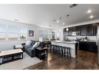 Bright, open-concept living room and kitchen with hardwood floors, granite countertops, and stainless steel appliances at 4680 Copeland Loop # 204, Highlands Ranch, CO 80126