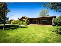 Charming log home with lush green lawn and mature landscaping creates a welcoming exterior at 2965 Wagner St, Strasburg, CO 80136