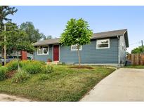 Charming single-story home with blue siding, a red door, and a well-maintained front yard and walkway at 2011 S Vallejo St, Denver, CO 80223