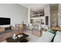 Bright living room with open kitchen, stainless steel appliances, and seating for four at kitchen island at 720 16Th St # 306, Denver, CO 80202