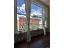 Stunning city views through large windows, showcasing historic brick building, hardwood floors, and custom curtains at 720 16Th St # 306, Denver, CO 80202