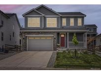 Charming two-story home featuring a gray exterior, stone accents, a two-car garage, and a cozy front porch at 1373 E Witherspoon Dr, Elizabeth, CO 80107