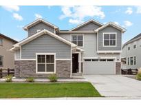 Beautiful two-story home with stone accents, gray siding, well-manicured lawn, and attached two car garage at 6263 E 142Nd Pl, Thornton, CO 80602