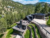 Stunning modern home featuring mountain views, tiered landscaping, and a sleek black exterior with an attached garage at 365 Bow Mountain Rd, Boulder, CO 80302
