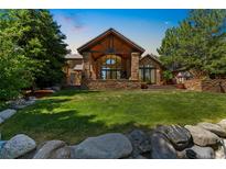 Beautiful backyard with a lush lawn, stone accents, and a covered patio perfect for outdoor entertaining at 5722 S Benton Way, Littleton, CO 80123