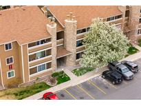 Aerial view showcases the condo's facade, stone details, balconies, mature landscaping, and convenient parking at 1074 S Dearborn St # 103, Aurora, CO 80012