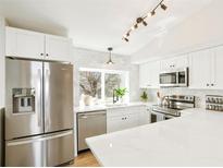 Bright kitchen features stainless steel appliances, white cabinets, marble backsplash, and quartz countertops at 12050 Dahlia Dr, Thornton, CO 80241