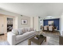 Bright living room showcasing modern decor, gray walls and flooring, adjacent to dining area and bedroom for seamless living at 3550 S Harlan St # 177, Denver, CO 80235