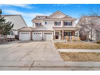 Charming two-story home with a three-car garage, a well-kept lawn, and a welcoming front porch at 11885 Helena St, Commerce City, CO 80022