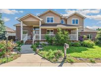 Charming two-story home featuring a welcoming porch, brick accents, manicured lawn, and beautiful landscaping at 942 Xenon Ct, Golden, CO 80401