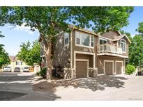 Inviting exterior showcasing a multi-level home with a balcony and three-car garage, enhanced by mature trees at 19663 E Mann Creek Dr # D, Parker, CO 80134
