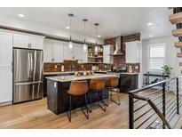 Modern kitchen features stainless steel appliances, brick backsplash, and a center island with bar stool seating at 5423 S Prince St # B, Littleton, CO 80120
