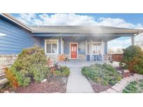 Charming covered front porch with bright red door and delightful decor, surrounded by inviting landscaping at 8910 Rutgers St, Westminster, CO 80031
