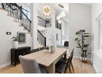 Bright dining room featuring hardwood floors, modern chandelier, and staircase with black metal railings at 4505 S Yosemite St # 362, Denver, CO 80237