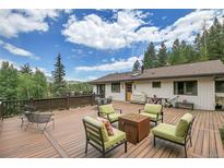 Wide view of a large outdoor deck with seating and a fire pit, perfect for entertaining and enjoying scenic views at 1774 Upper Bear Creek Rd, Evergreen, CO 80439