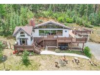 Mountain home with large deck and fire pit surrounded by lush forest at 1774 Upper Bear Creek Rd, Evergreen, CO 80439