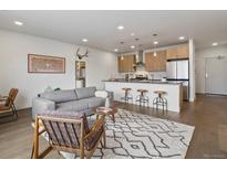 Open-concept living room and kitchen with modern finishes and hardwood flooring at 1898 S Bannock St # 209, Denver, CO 80223
