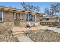 Charming brick home featuring a cozy front porch with two chairs and a well-maintained yard at 7950 Maria St, Westminster, CO 80030