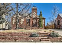 Charming brick home with detailed masonry work, a landscaped yard, and a unique chimney design at 1120 Holly St, Denver, CO 80220