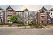Condo's exterior with grey siding, brick accents, and landscaped grounds offers curb appeal at 14221 E 1St Dr # 303, Aurora, CO 80011