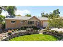 Charming brick home featuring a lush front yard with stone accents and mature landscaping at 3570 W Pimlico Ave, Englewood, CO 80110