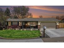 Charming ranch-style home with well-manicured lawn, brick accents, and a cozy, inviting entrance under a colorful sky at 7960 Estes Ct, Arvada, CO 80005