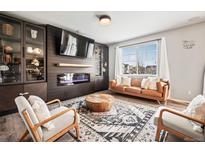 Modern living room with a fireplace, large TV, display cabinets and lots of natural light at 2688 Loon Cir, Castle Rock, CO 80104