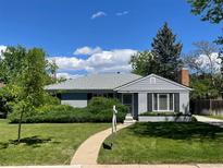 Charming gray-painted home featuring a manicured lawn and mature landscaping at 1030 Krameria St, Denver, CO 80220