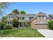 Charming two-story home boasts a landscaped yard and inviting curb appeal with well-manicured lawn and mature plantings at 11453 E Orchard Pl, Englewood, CO 80111