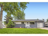 Well-maintained single-story home with a gray brick and white facade and green lawn at 5150 W Colgate Pl, Denver, CO 80236