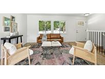 Bright living room featuring stylish decor, a brown leather couch, and two comfortable accent chairs at 1380 Holly E Dr, Broomfield, CO 80020