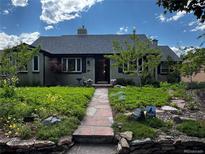 Charming single-story home featuring a stone walkway and a beautifully landscaped front yard with lush greenery and flowers at 1185 Glencoe St, Denver, CO 80220