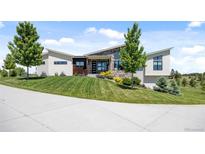 Striking contemporary home featuring a stone facade, unique roofline, and meticulously landscaped front yard at 10205 Inspiration Dr, Parker, CO 80138