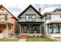 Charming two-story home with a covered front porch, green siding, and a well-maintained lawn at 940 N Ogden, Denver, CO 80218