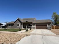 Charming single-Gathering home with a well-manicured lawn, concrete driveway, and stone facade accents at 504 Elizabeth Ave, Platteville, CO 80651