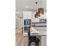 Bright kitchen features modern stainless appliances, white cabinetry, granite counters, and pendant lighting at 21893 E Tufts Cir, Aurora, CO 80015